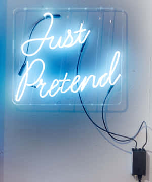藍色霓虹燈牌，以草書字體寫著「Just Pretend」，安裝在牆上。 — Pixel Fold 壁紙