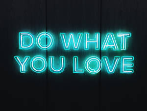 霓虹燈牌寫著 do what you love 在深色木背景上 — 愛情語錄 GIF 壁紙