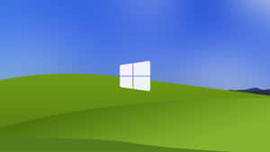 藍天下綠色山丘上的Windows標誌 — 7680x4320 壁紙