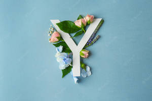 在藍色背景上，字母Y裝飾有粉紅玫瑰、藍色繡球花和綠葉。 — 字母 y 壁紙