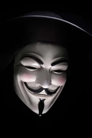 一個白色的 Guy Fawkes 面具，帶著一個大大的笑容和黑色帽子，在黑色背景前。 — 駭客面具 壁紙