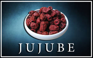 白色碗裝滿皺紋紅棗，置於深藍綠色背景上，帶有「JUJUBE」文字。 — 水果 壁紙