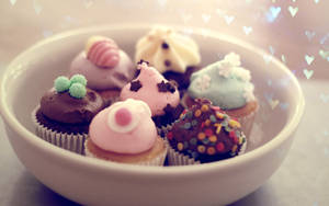 一碗裝飾有彩色糖粒和心形散景燈光的杯子蛋糕。 — 杯子蛋糕 壁紙