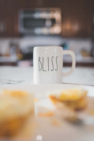 白色馬克杯有 bliss 字樣，在廚房檯面上糕點盤旁邊。 — IQOO Pad5 Pro 壁紙