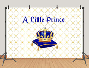 一個皇家藍色皇冠放在軟墊上，帶有「A Little Prince」文字，背景為金色菱格紋。 — 深紅之王 壁紙