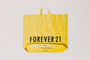 一個黃色Forever 21購物袋，上面有黑色文字，背景為白色。 — 永遠21 壁紙