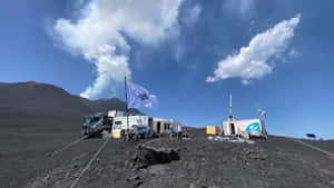 火山地形上的研究營地，遠處山峰升起煙霧。 — 山景 壁紙