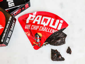 破爛的Paqui洋芋片袋，大理石上散落著破碎的黑色玉米片。 — 4:3 壁紙