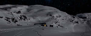 星空下溫暖發光且有腳印的積雪山洞 — 山景 壁紙