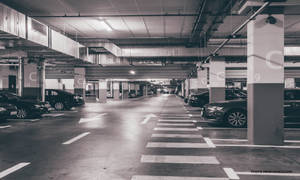空的地下停車場，有停泊的汽車和地板上的白色方向箭頭。 — 灰色 壁紙