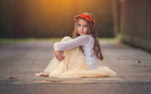 戴著橙色花冠的小女孩坐在夕陽下的木甲板上。 — 孤獨 壁紙