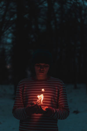 在雪夜森林中手持點燃蠟燭的人。 — 火焰動畫 壁紙