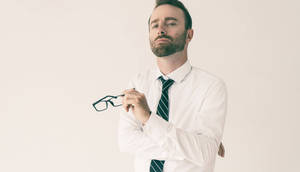 一個穿著商務服裝的男人，手持眼鏡，神情若有所思。 — 模特兒 壁紙