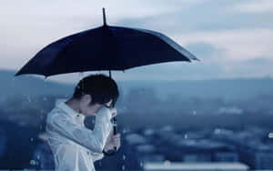 人在城市屋頂上拿著黑色雨傘在雨中遮臉，黃昏時分。 — 孤獨悲傷 壁紙