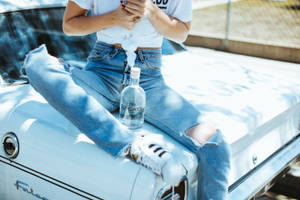 人坐在復古汽車引擎蓋上，手持伏特加瓶 — 復古 壁紙