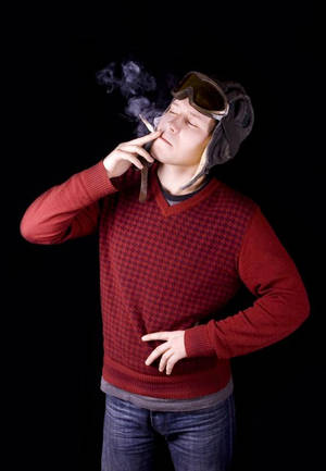 穿著紅色毛衣和飛行員帽的男人抽煙，煙霧上升。 — 抽菸 壁紙