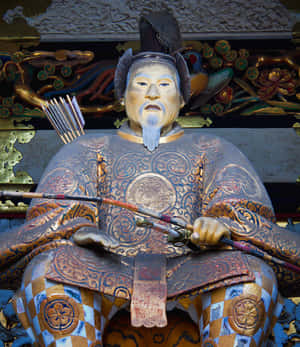 一個坐在裝飾性神社下方、穿著精細盔甲、手持弓箭的武士雕像。 — 小米 Mix Flip 2 壁紙