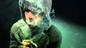 穿著連帽衫的人在昏暗的綠色燈光下，手持點燃的大麻煙並呼出煙霧。 — ASAP Rocky 壁紙