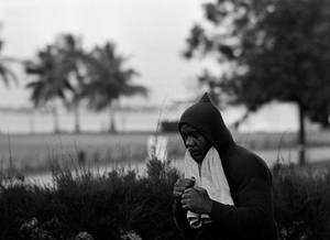 穿著連帽衫的男人在棕櫚樹和灌木叢附近的戶外拿著毛巾。 — Running 壁紙