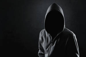 穿著深色連帽衫的匿名人物，臉部隱藏在陰影中。 — 森林 壁紙