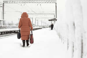 穿著冬季外套的人在積雪的火車站月台上行走。 — 寒冷 壁紙