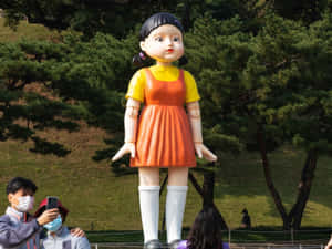 公園裡的大型公仔雕像，有遊客在拍照 — 067 魷魚遊戲 壁紙