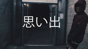 穿連帽衫的人靠著磚牆，旁邊是敞開的門口，帶有日文文字。 — Scarlxrd 壁紙