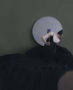 人拿著紫色花映照在圓鏡中，背景是綠色牆壁。 — 美麗的公主 壁紙