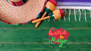 綠色木頭上的Cinco de Mayo慶祝物品，包括帽子、沙鈴和毯子。 — 慶祝 壁紙