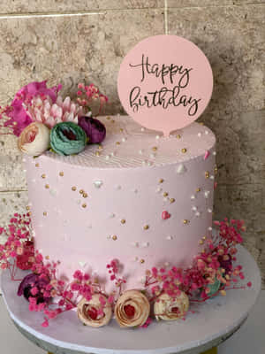 一個粉紅色生日蛋糕，用花朵和糖粒裝飾，並有 happy birthday 蛋糕插牌。 — 2048x2732 壁紙