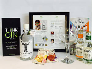 Think Gin Club 訂閱盒，內有琴酒瓶、雞尾酒指南和小吃，整齊排列在白色表面上。 — 品牌 壁紙