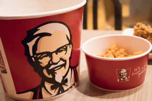 木桌上裝滿炸雞的紅色KFC桶。 — 肯德基 壁紙