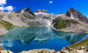 高山湖泊在清澈的藍天下映照著積雪的山脈。 — 巴基斯坦國旗 壁紙