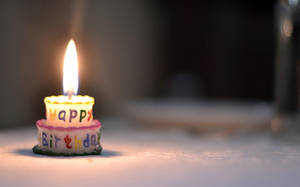 一個細小的生日蠟燭，上面有 'Happy Birthday' 文字正在明亮地燃燒。 — 慶祝 壁紙