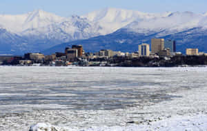 結冰的湖泊與城市和白雪覆蓋的山脈在背景中 — 雪景 GIF 壁紙