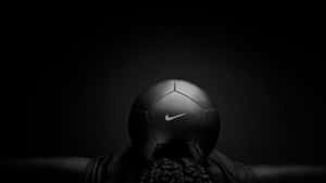 在黑暗環境中將黑色Nike足球舉過頭頂的人 — 黑色高畫質桌布 壁紙