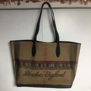 經典格紋Burberry托特包掛在牆上，上方有銅色閃片。 — Burberry 壁紙