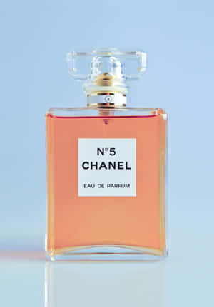 Chanel No 5 香水瓶，裝有蜜桃色液體，置於藍色背景上。 — 華為Pura X Max 壁紙