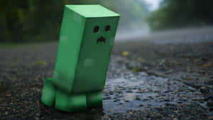 綠色Minecraft爬行者站在雨中濕漉漉的路面上，背景有森林。 — 可愛 Minecraft 壁紙