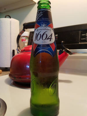 廚房檯面上紅色水壺旁邊的綠色Kronenbourg 1664啤酒瓶。 — 啤酒 壁紙