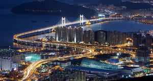 夜晚海灣上的一座發光吊橋，伴隨著燈火通明的城市建築和高速公路。 — 孟買 壁紙