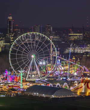 夜間遊樂園，摩天輪和雲霄飛車，以城市燈光為背景。 — 冬季房屋 壁紙