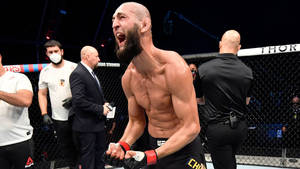 UFC拳手在八角籠中與官員一起慶祝勝利。 — 運動 壁紙