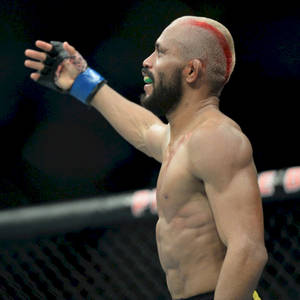 一位勝利的MMA戰士在八角籠內以紅色條紋頭髮慶祝。 — 終極格鬥冠軍賽 壁紙