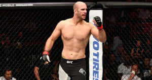 一個光頭MMA戰士在UFC八角籠內慶祝勝利，粉絲歡呼。 — 終極格鬥冠軍賽 壁紙