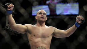 一位勝利的MMA拳手在八角籠中舉起拳頭。 — 運動 壁紙