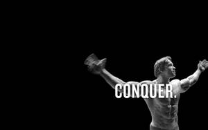 肌肉男舉起啞鈴，帶有「CONQUER」文字疊加。 — 動力 壁紙