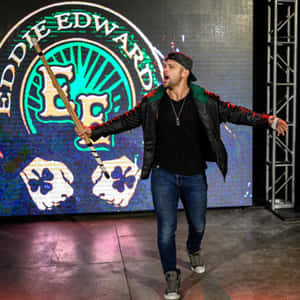 摔角手 Eddie Edward 在明亮的燈光下拿著杖在舞台上表演。 — 摔角 壁紙