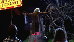 Beetlejuice 在夜晚的發光標誌下於岩石上表演。 — 陰間大法師 壁紙