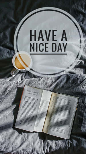灰色床上的咖啡杯和打開的書，帶有 'Have a Nice Day' 文字疊加。 — 祝你有美好的一天 壁紙